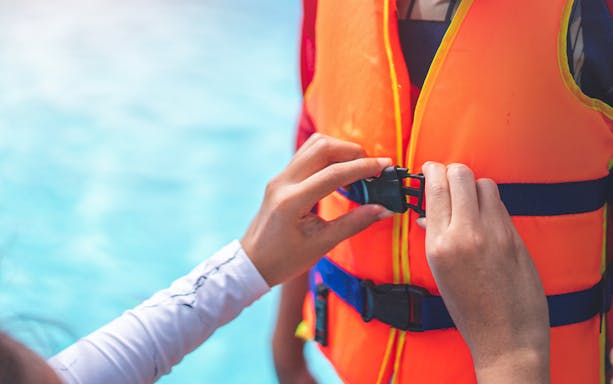 Person fastening a life jacket buckle