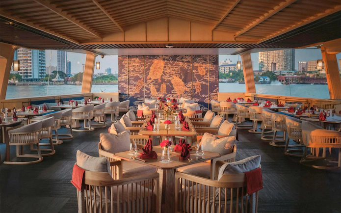 Elegant dining area on Okura Cruise Bangkok with river view and decorative wall art.