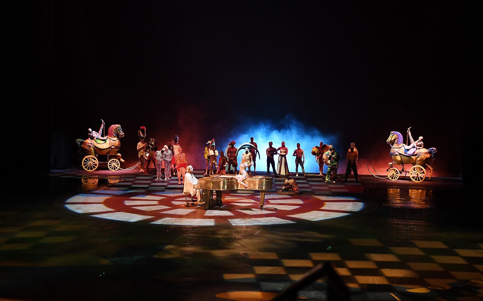 Performers on stage with colorful costumes and props in a theatrical show.