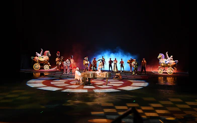 Performers on stage with colorful costumes and props in a theatrical show.