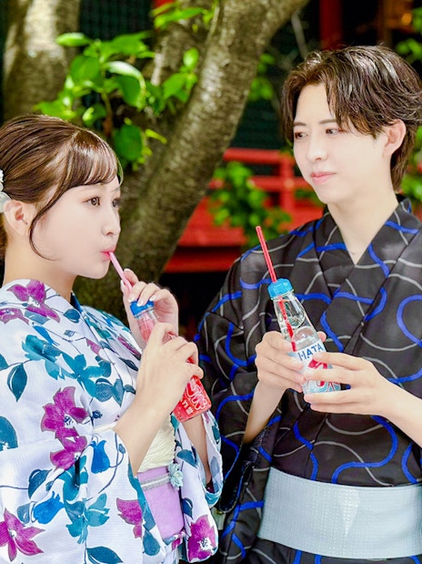Couple in traditional kimono enjoying soft drinks at a Japanese temple.