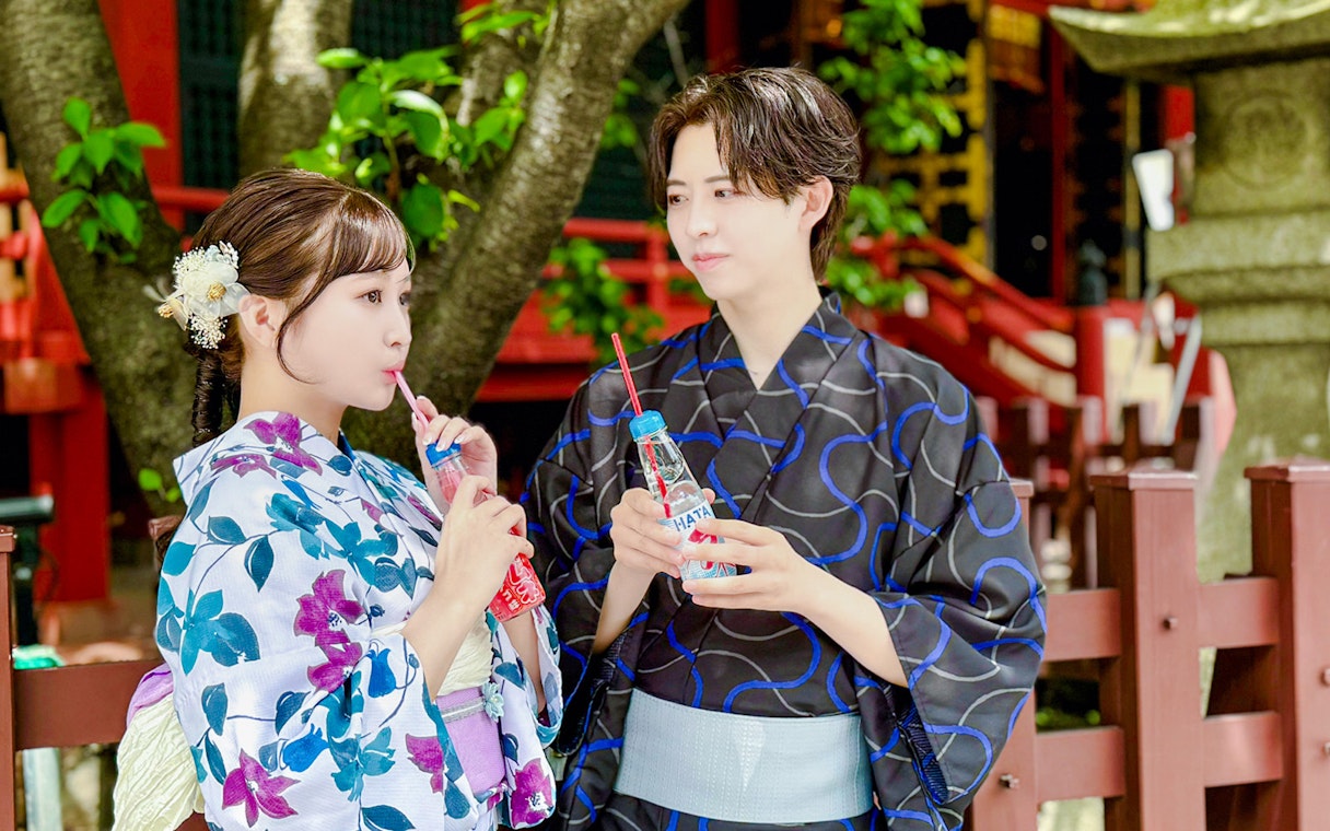 Couple in traditional kimono enjoying soft drinks at a Japanese temple.