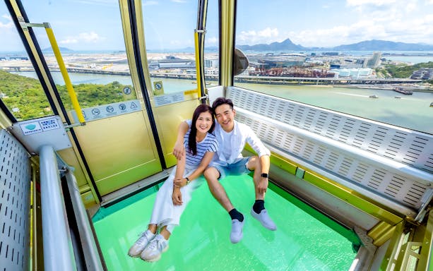Couple enjoying view from crystal cable car at Ngong Ping 360, Hong Kong.