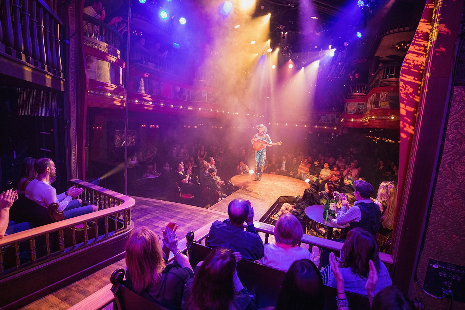 Performer on stage at Atomic Saloon Show with audience in theater setting.
