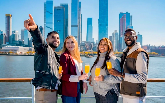 Group enjoying drinks on Bateaux New York Premier Dinner Cruise with city skyline in background.