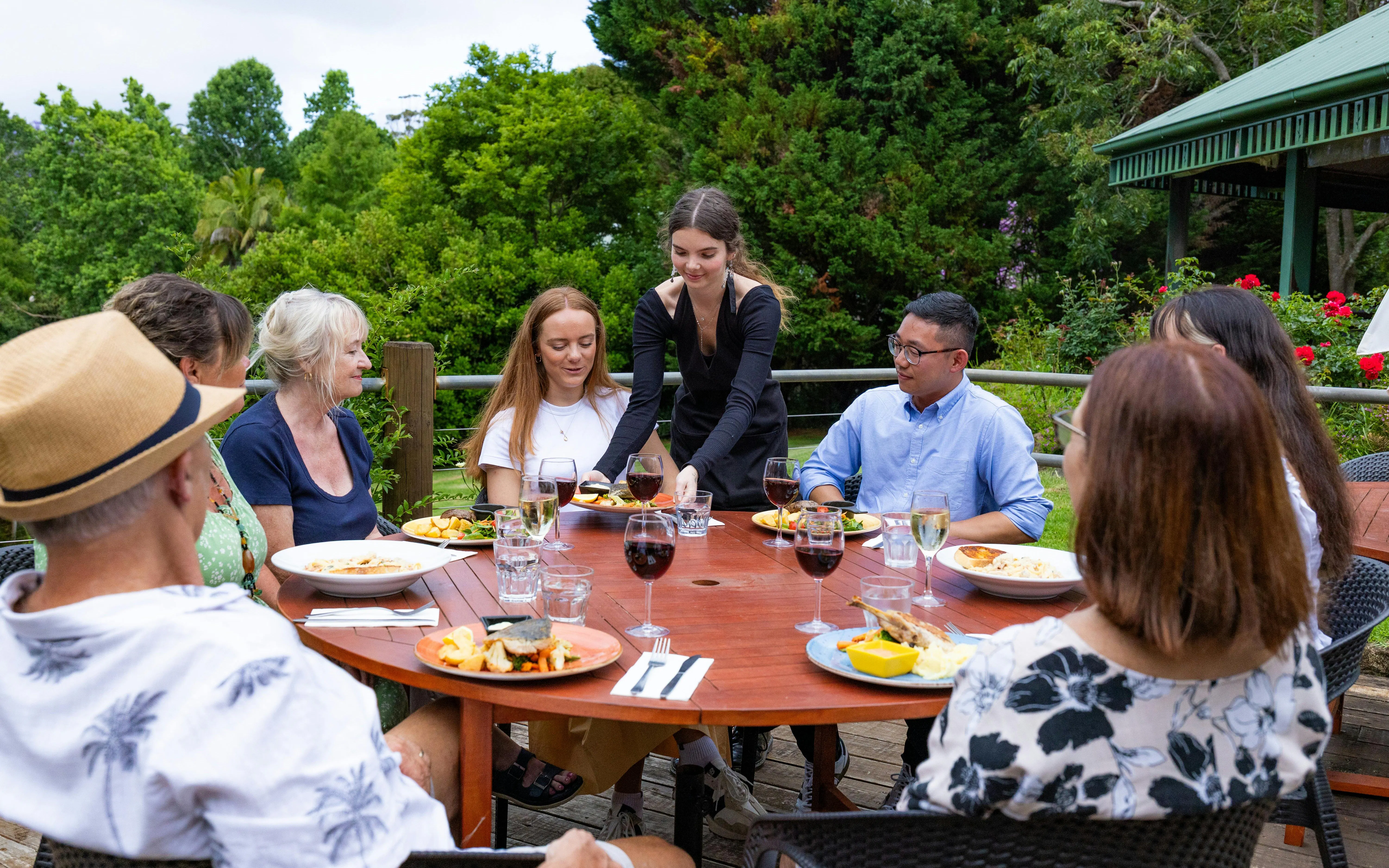 Group dining outdoors at Tamborine Mountain with diverse dishes and wine.