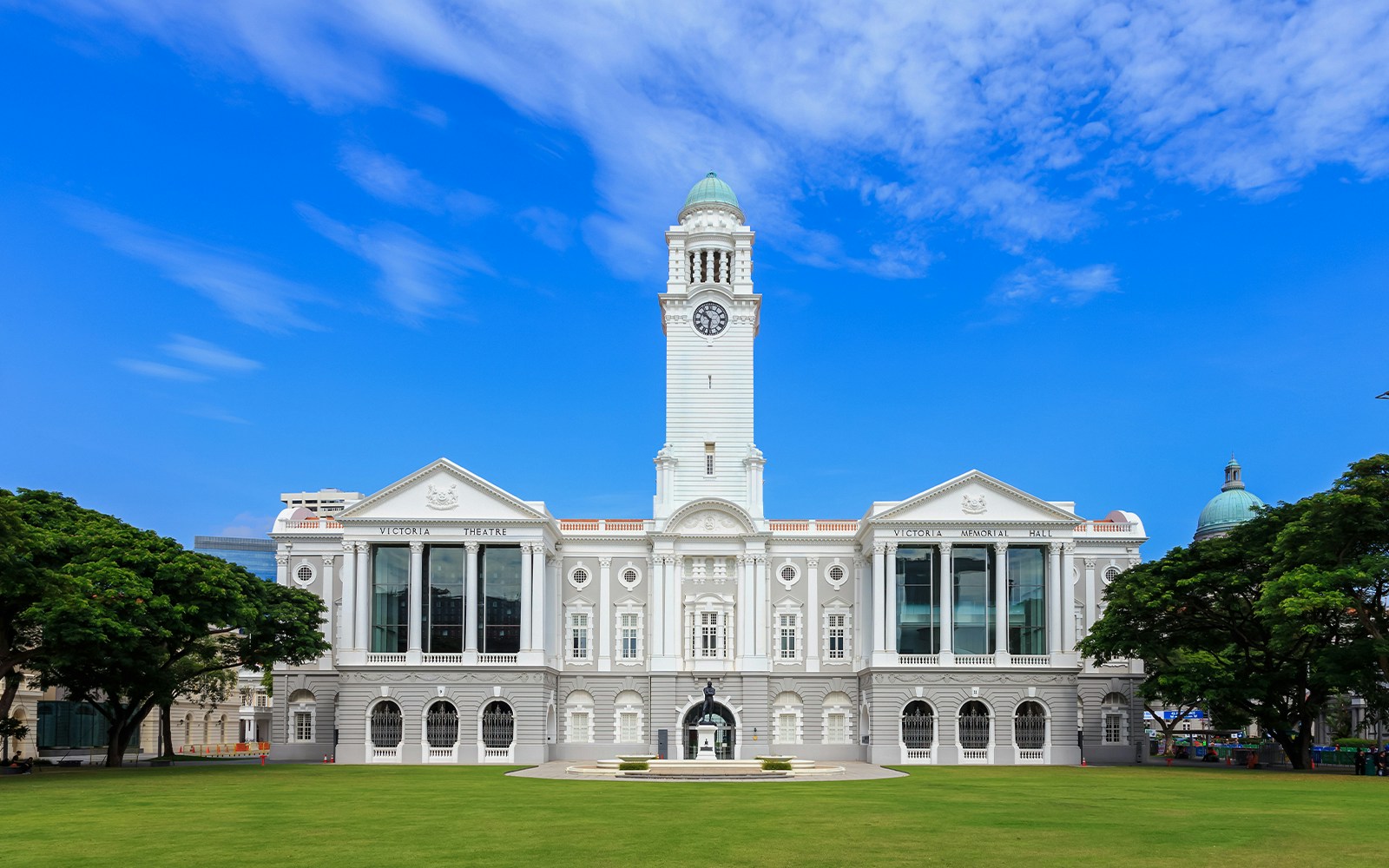 Victoria Theatre in Singapore with clock tower and green lawn.