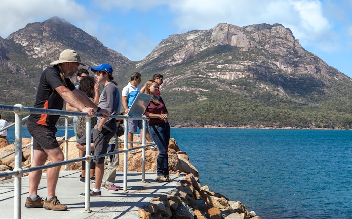 Visitors enjoying the view of Wineglass Bay with mountains in the background, Tasmania.
