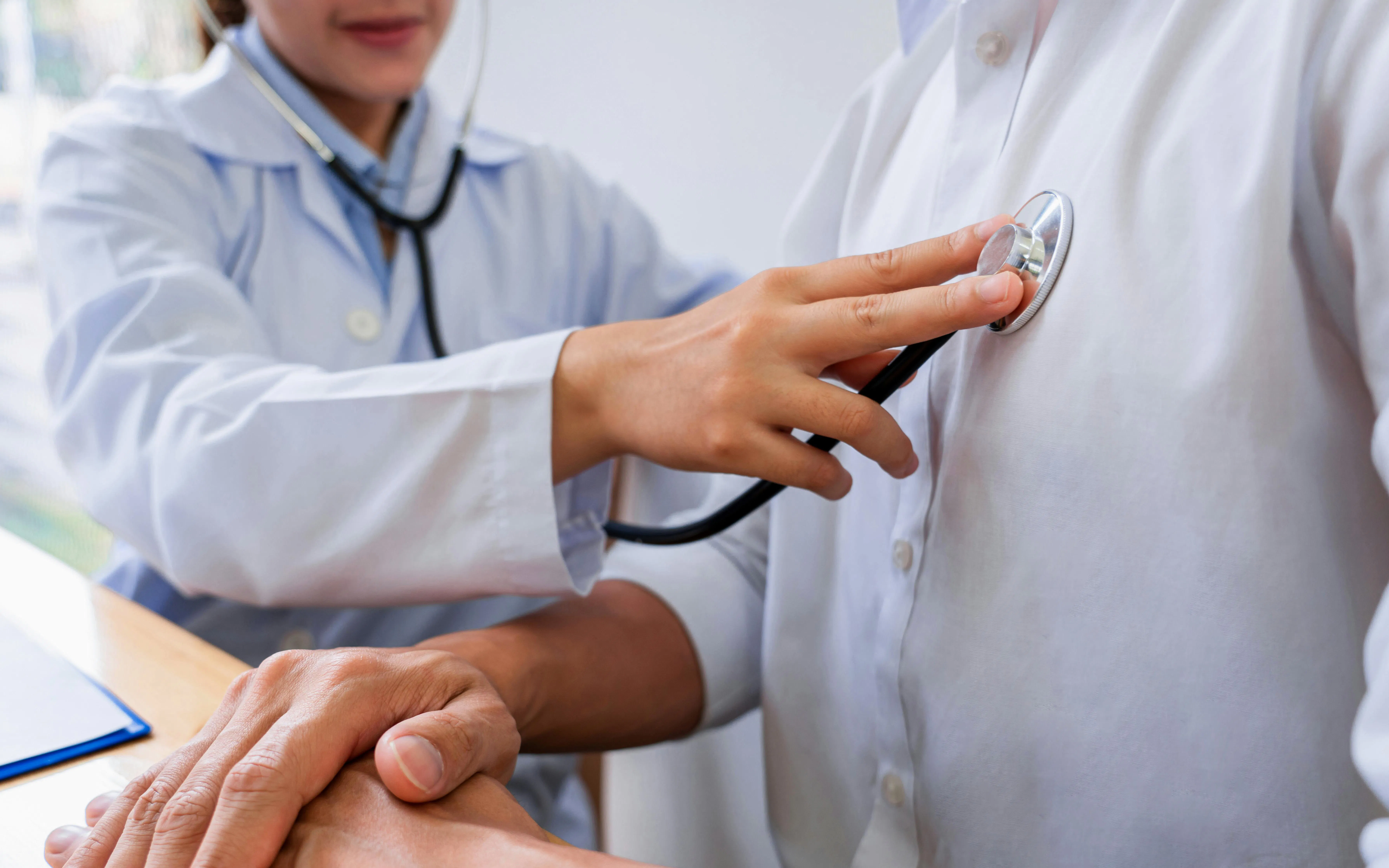 Doctor using stethoscope on patient's chest during examination.