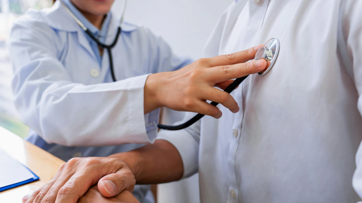Doctor using stethoscope on patient's chest during examination.