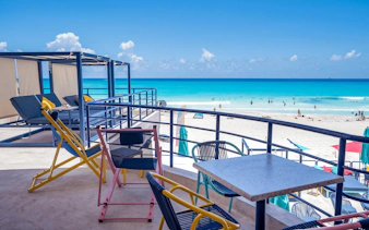 Outdoor seating overlooking Coco Bongo Beach with turquoise water and people swimming.