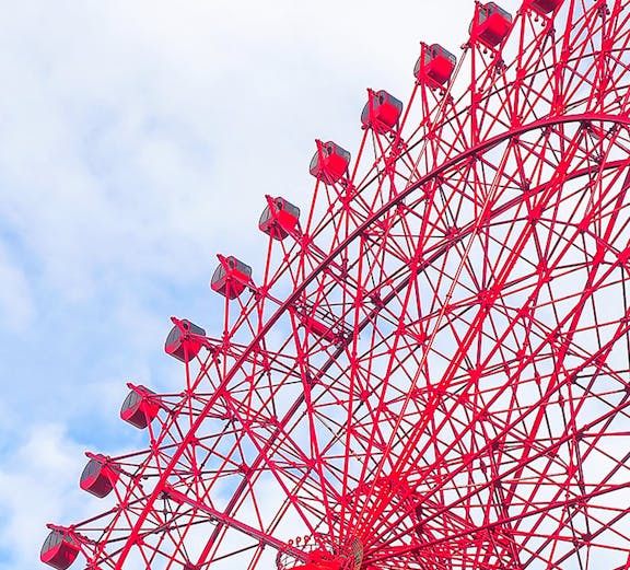 Red HEP Ferris Wheel against a cloudy sky.