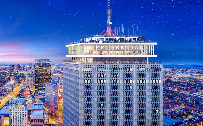 Prudential Tower illuminated at night with cityscape view, Boston.