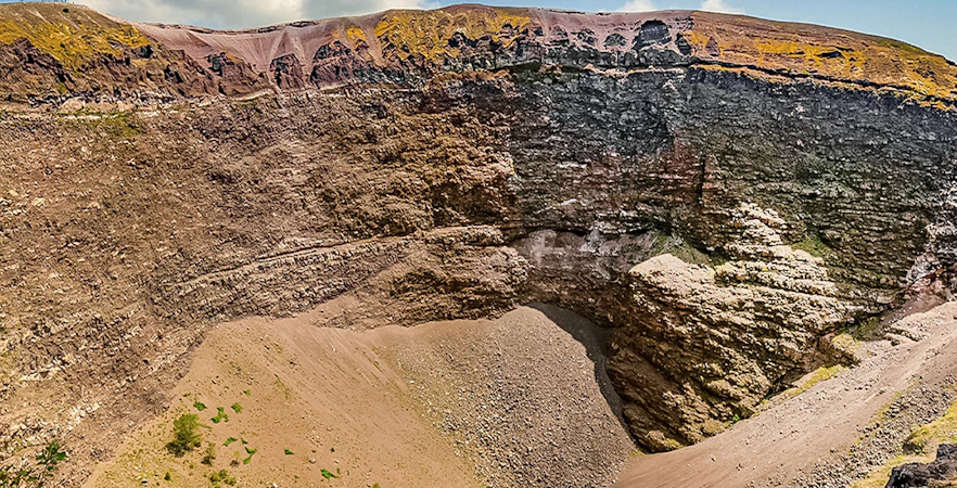 Mount Vesuvius crater with rocky terrain and clear sky in Naples, Italy.