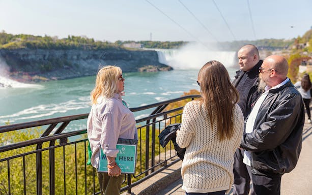 Visitors viewing Niagara Falls from a railing during a half-day tour.
