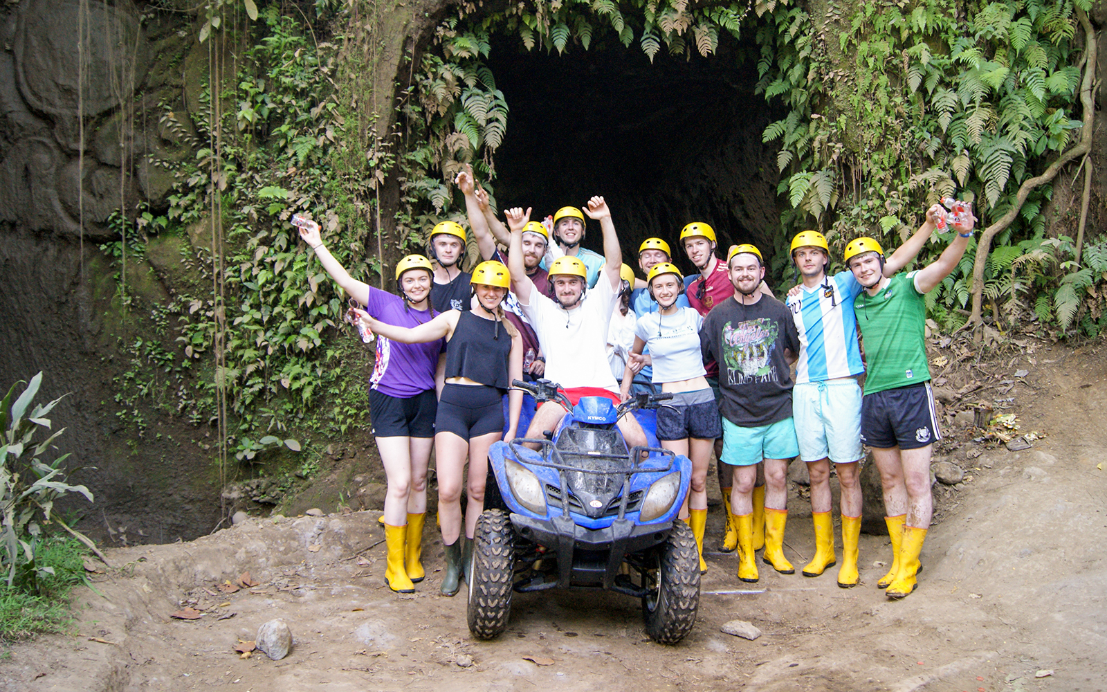 Group of people in helmets and boots posing with an ATV in a jungle setting, Bali.