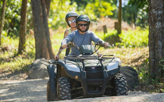 Two people riding a quad bike on a forest trail during Bel Ombre tour.