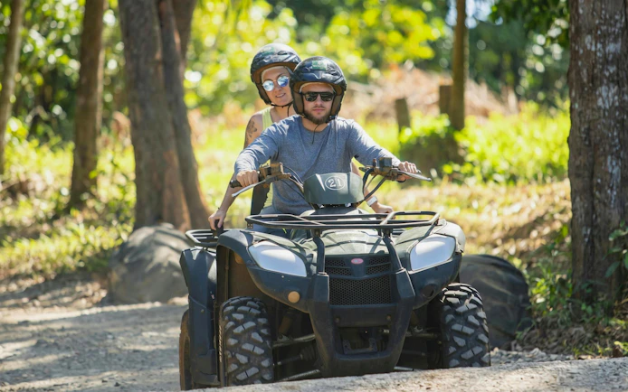 Two people riding a quad bike on a forest trail during Bel Ombre tour.