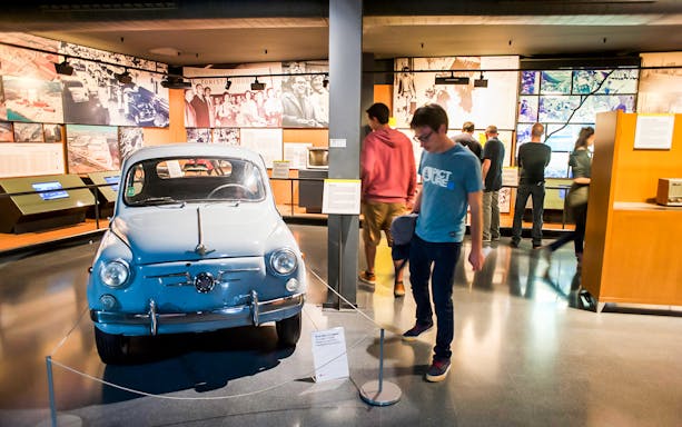 Vintage car exhibit at History Museum of Catalonia with visitors exploring displays.