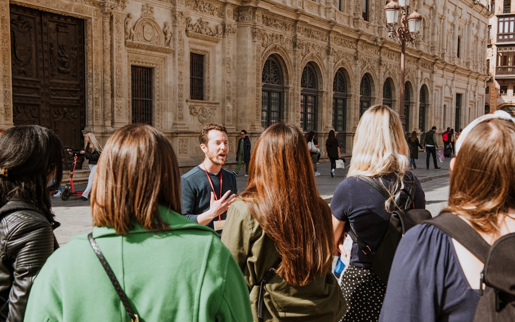 Group on a guided walking tour in front of historic building in Seville, Spain.