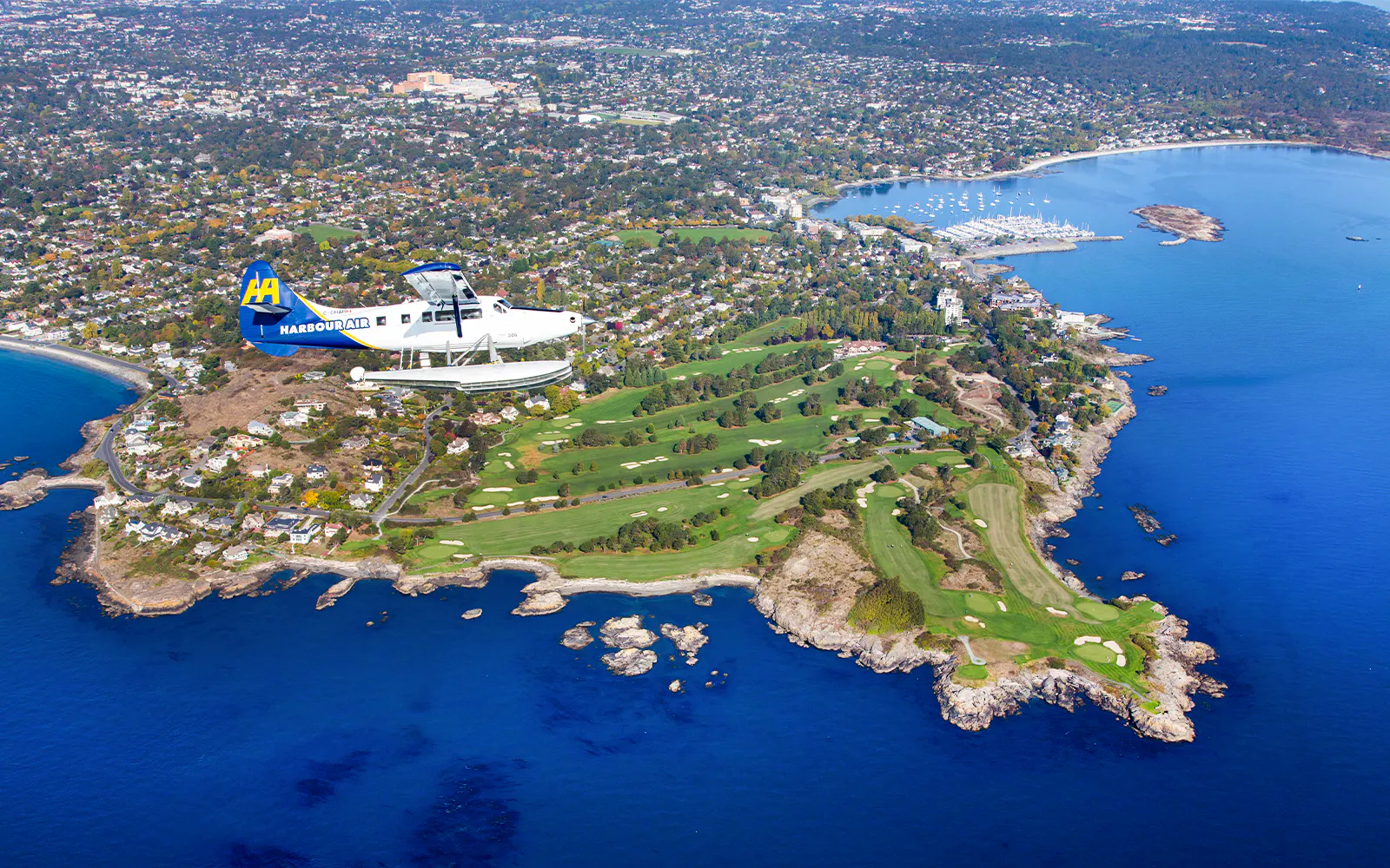 Seaplane flying over Victoria coastline and golf course during scenic tour.