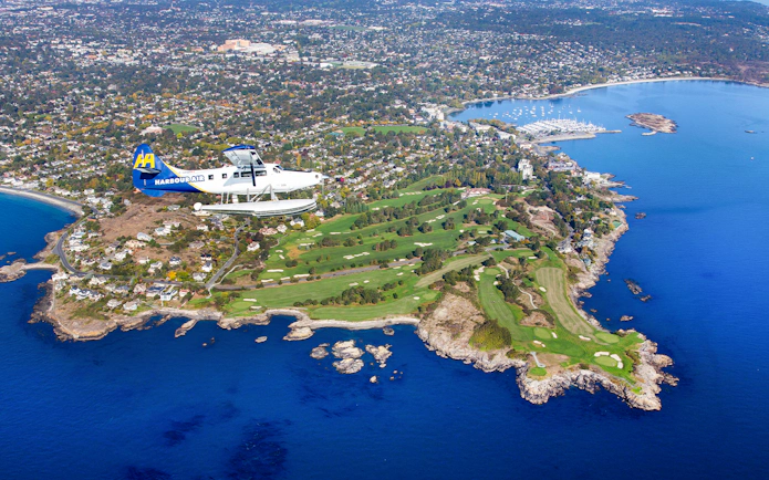 Seaplane flying over Victoria coastline and golf course during scenic tour.