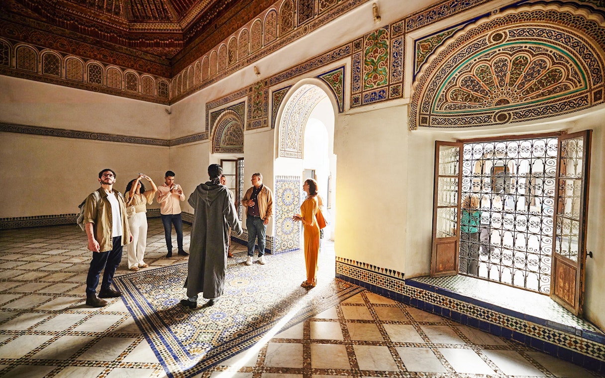 Visitors exploring ornate interior of Bahia Palace, Marrakech, Morocco.