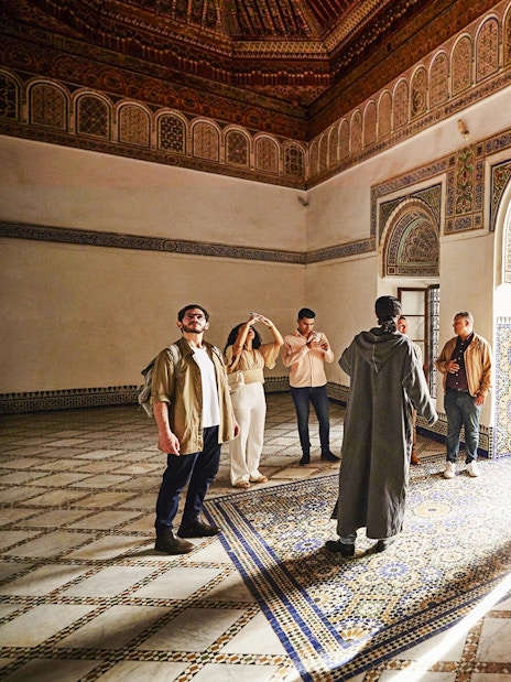Visitors exploring ornate interior of Bahia Palace, Marrakech, Morocco.
