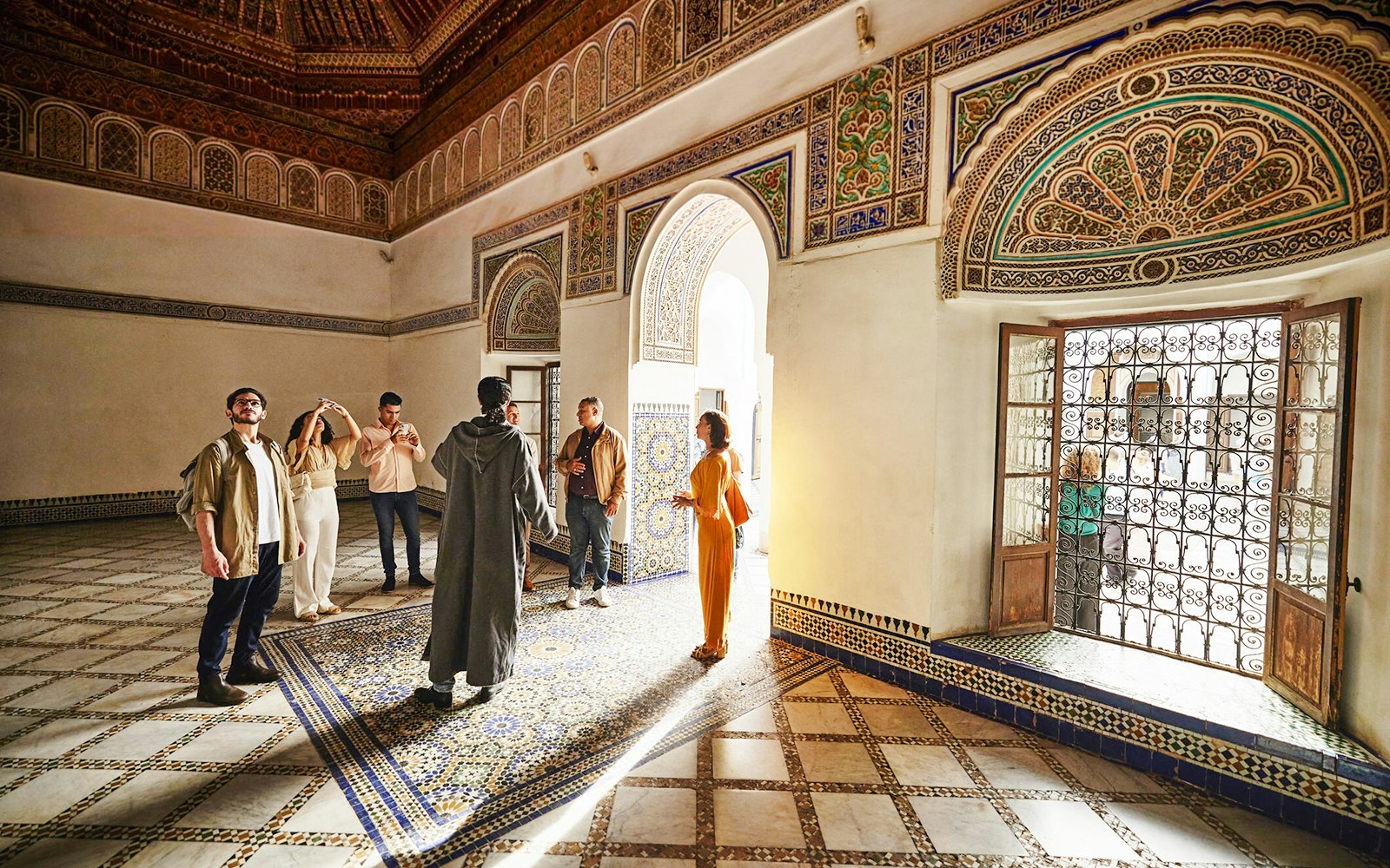 Visitors exploring ornate interior of Bahia Palace, Marrakech, Morocco.