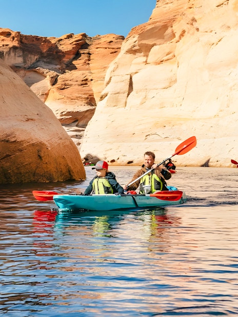 Kayakers paddling on Lake Powell near Antelope Canyon's sandstone cliffs.