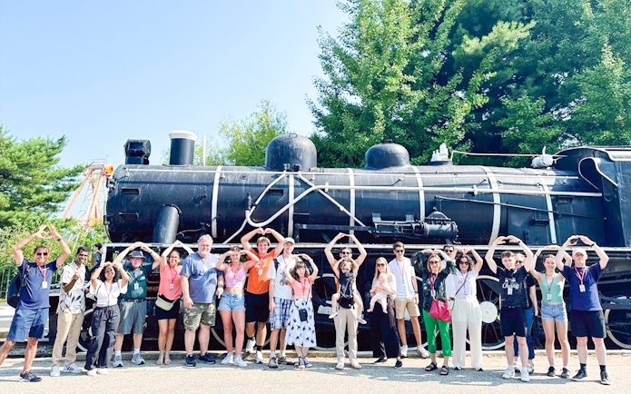 Tourists posing in front of Korean War steam locomotive at Imjingak Park on DMZ tour.