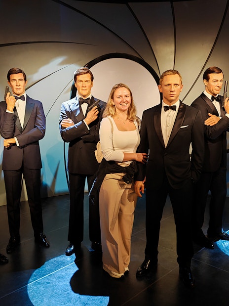 Wax figures of James Bond actors at Madame Tussauds with a visitor.
