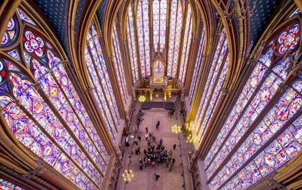 Group tour inside Sainte Chapelle, Paris, with vibrant stained glass windows.