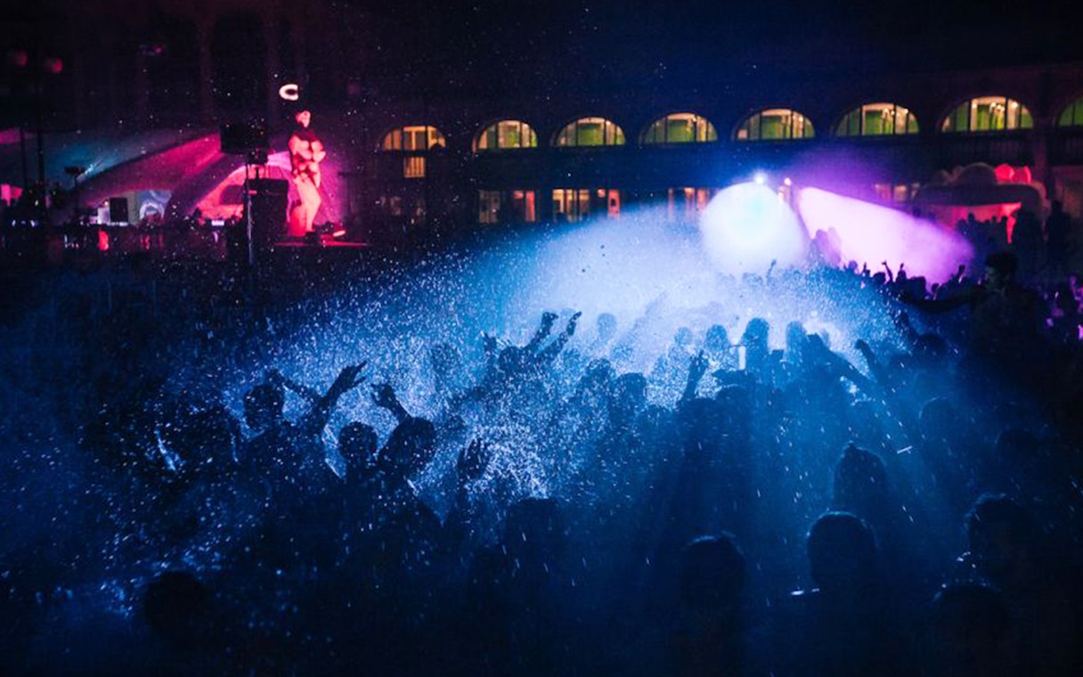 Crowd enjoying a night party with lights and water effects in Budapest.
