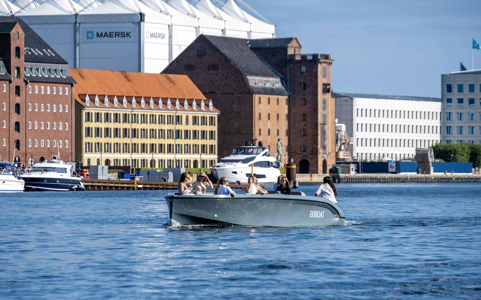 Boat tour in Copenhagen harbor with cityscape backdrop, featuring guests enjoying the view.