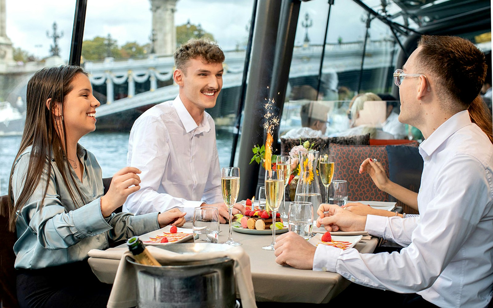Guests enjoying a festive meal on a Paris Christmas cruise with Eiffel Tower views.