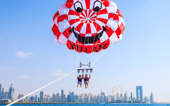 Parasailing over Dubai skyline with colorful parachute.