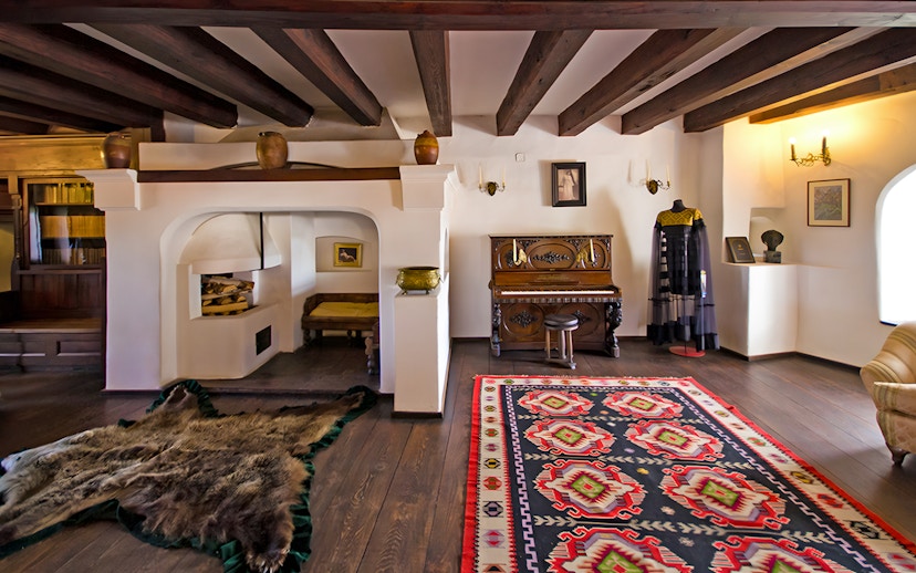 Bran Castle hall with medieval furniture, stone walls, and a colorful rug in Transylvania, Romania.