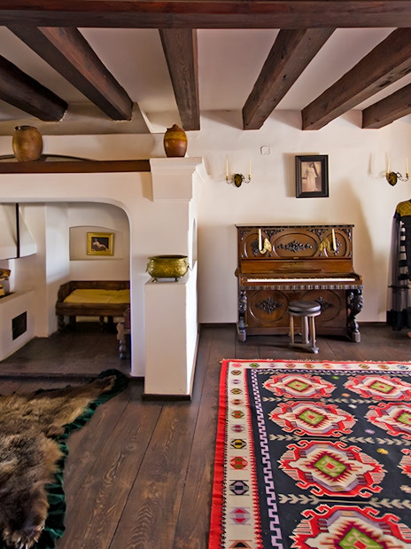 Bran Castle hall with medieval furniture, stone walls, and a colorful rug in Transylvania, Romania.