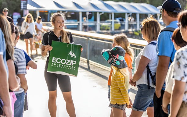 Guide holding EcoZip Adventures sign for Waiheke Island zipline shuttle pickup.