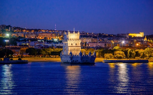 Belem Tower illuminated at night during a Lisbon cruise.