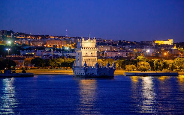 Belem Tower illuminated at night during a Lisbon cruise.