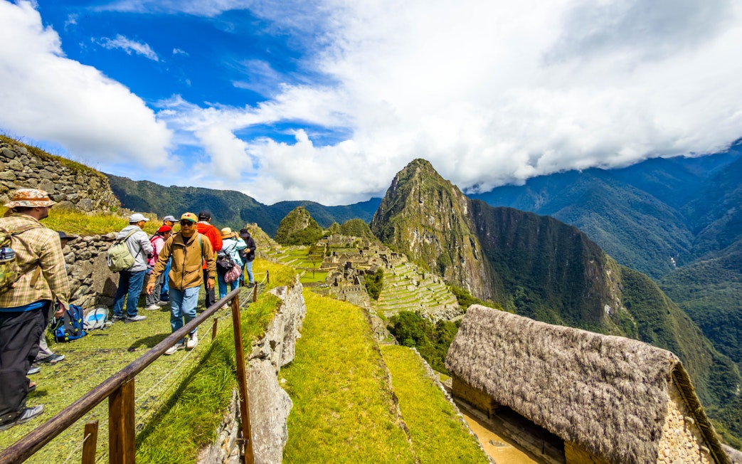 Tourists with guide overlooking Machu Picchu ruins in Peru.