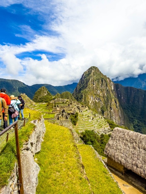 Tourists with guide overlooking Machu Picchu ruins in Peru.