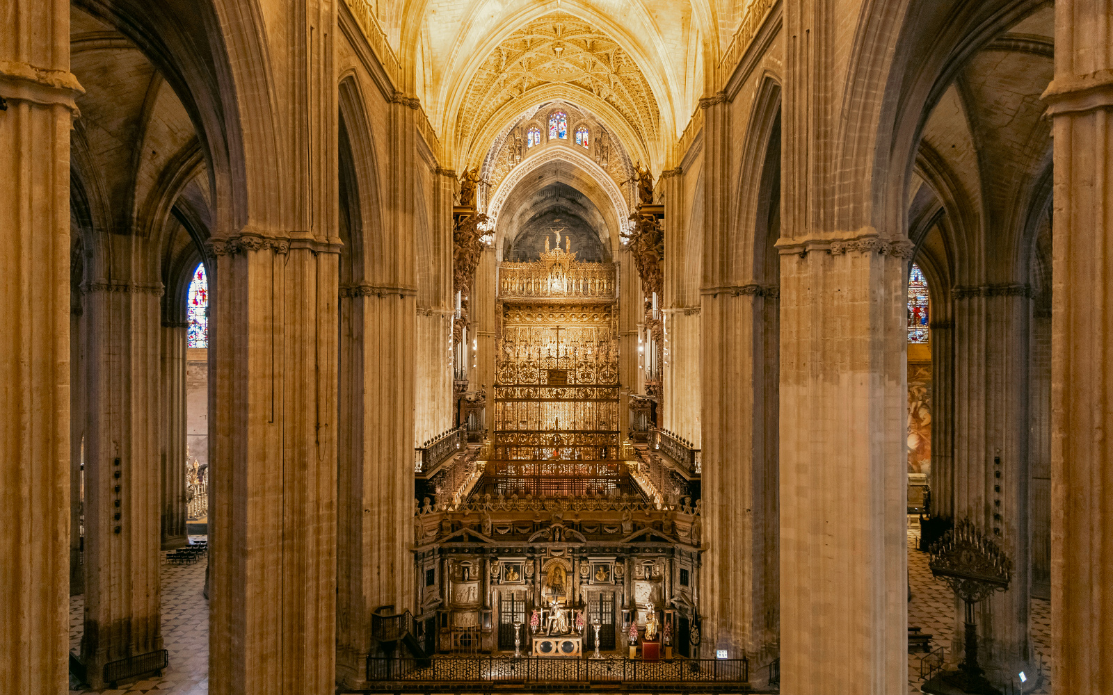 Seville Cathedral interior with ornate altar and vaulted ceilings.