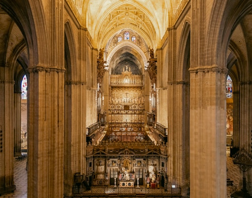 Seville Cathedral interior with ornate altar and vaulted ceilings.