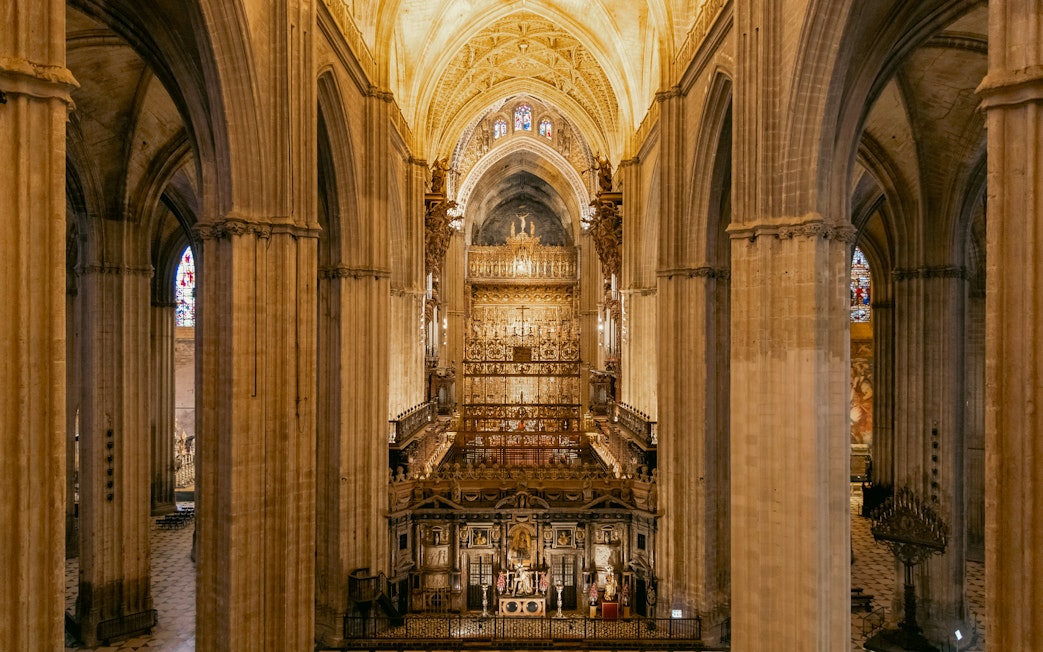 Seville Cathedral interior with ornate altar and vaulted ceilings.