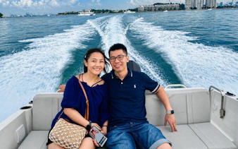 Couple enjoying a speedboat cruise with city skyline in the background, Singapore.
