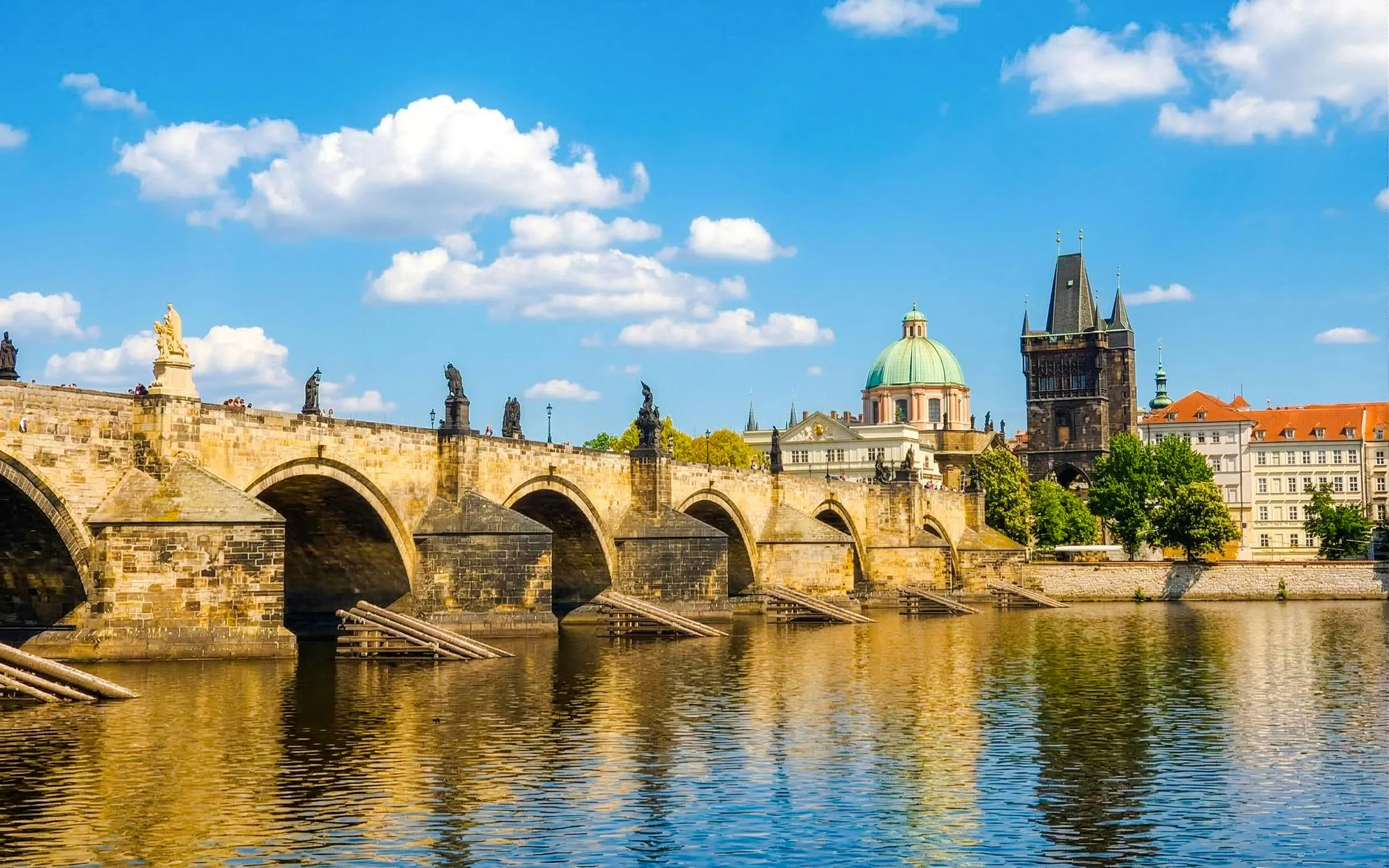 Charles Bridge over Vltava River with Prague skyline in the background.