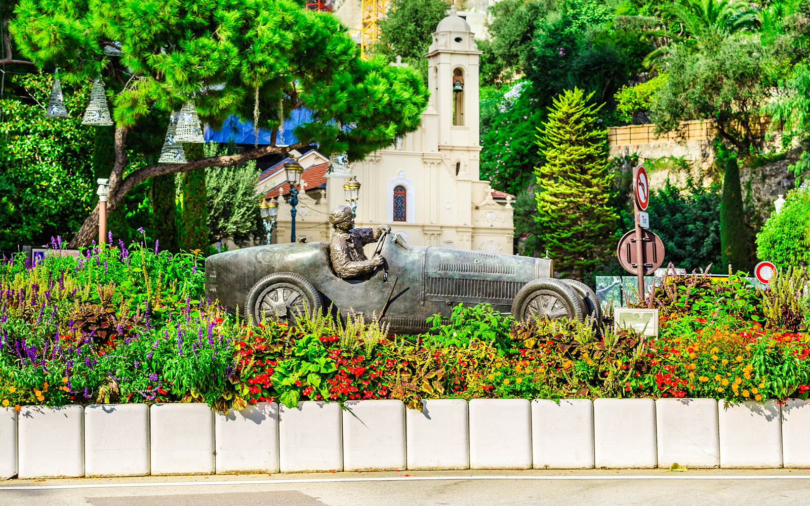 Bronze race car statue surrounded by flowers on Monaco Formula 1 Walking Tour.